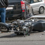 broken motorcycle closeup beside the car. an accident on the road in the city on a sunny day involving a motorcycle and a car